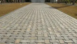 Long herringbone paver driveway leading to a home