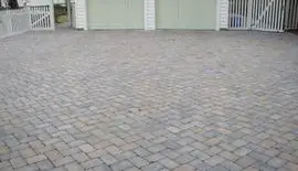 Multi-tone paver driveway in front of a white coastal home