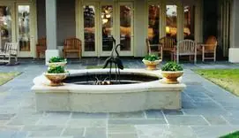 Bluestone courtyard with a stone fountain and rocking chairs
